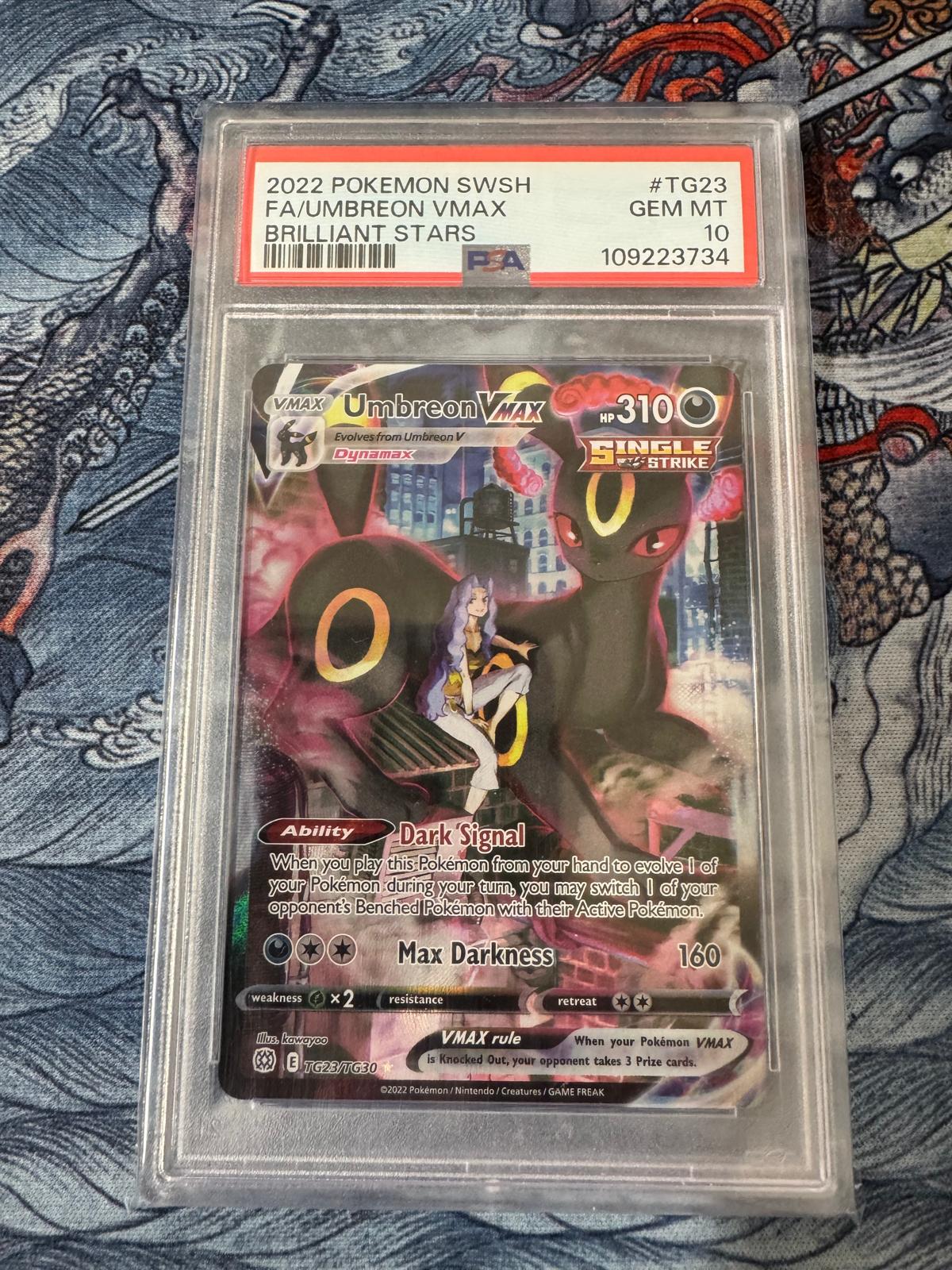 Pokémon trading card featuring Umbreon VMAX in a protective case on a patterned background